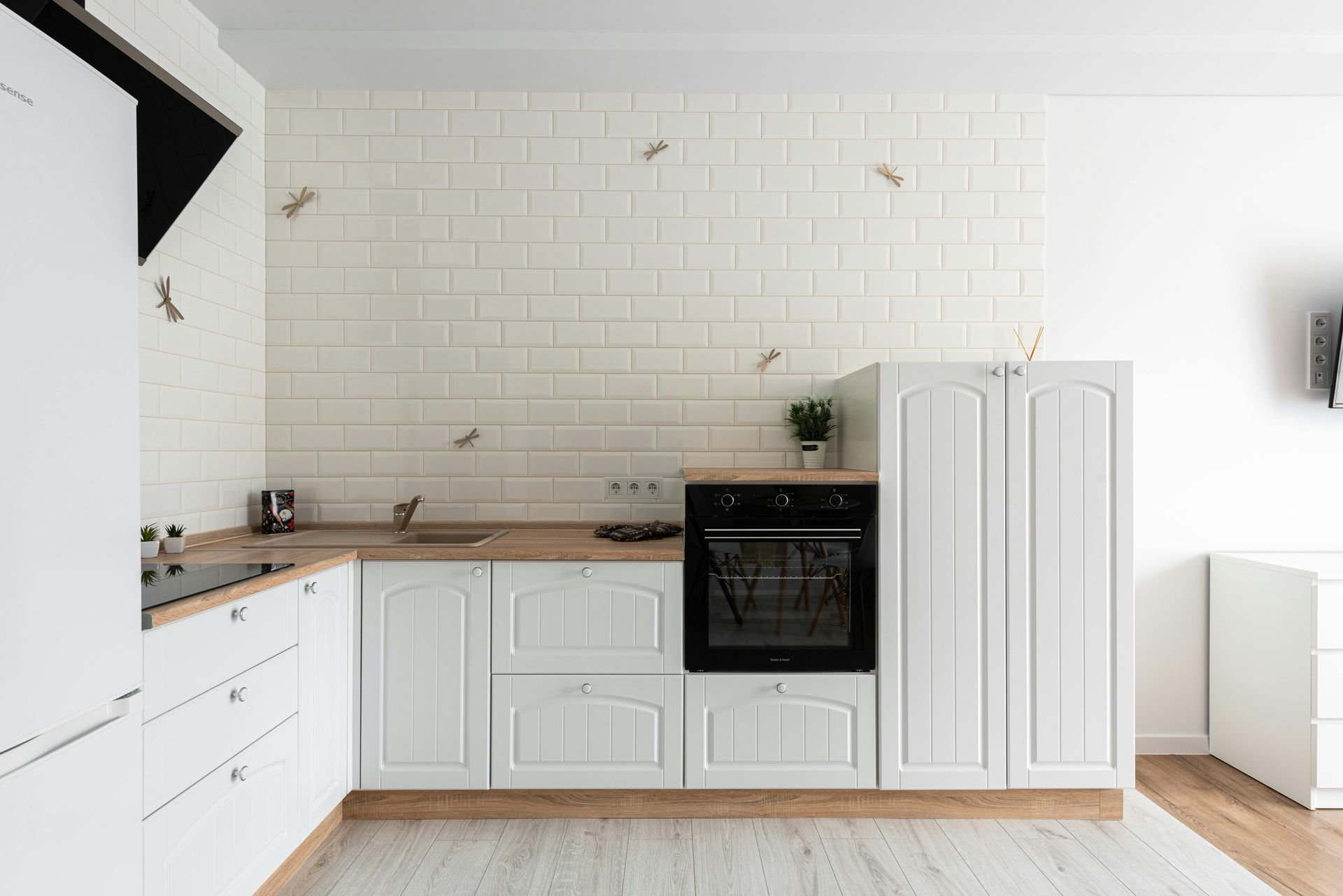 White kitchen with wooden countertops, cabinets, and oven. Light brick wall.