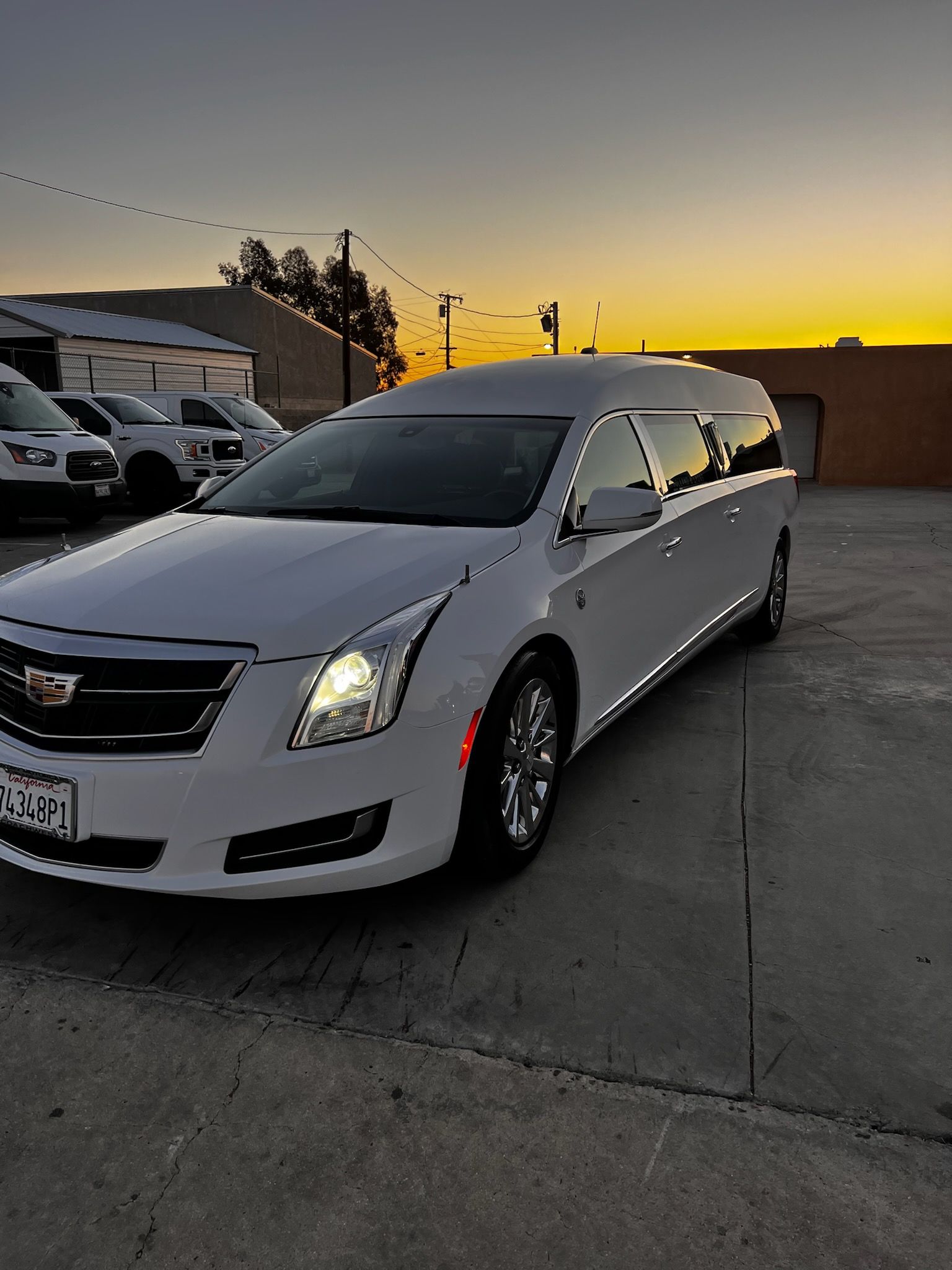 White hearse parked outdoors at dusk.