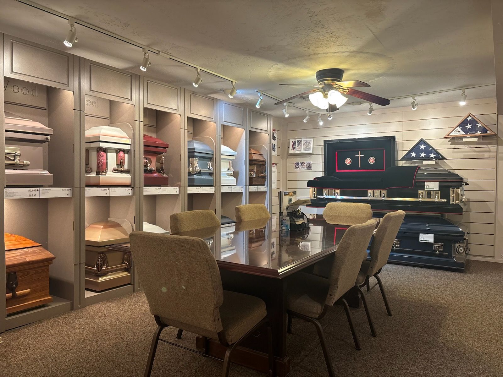 Funeral home showroom with a display of caskets and an ornate meeting table and chairs.