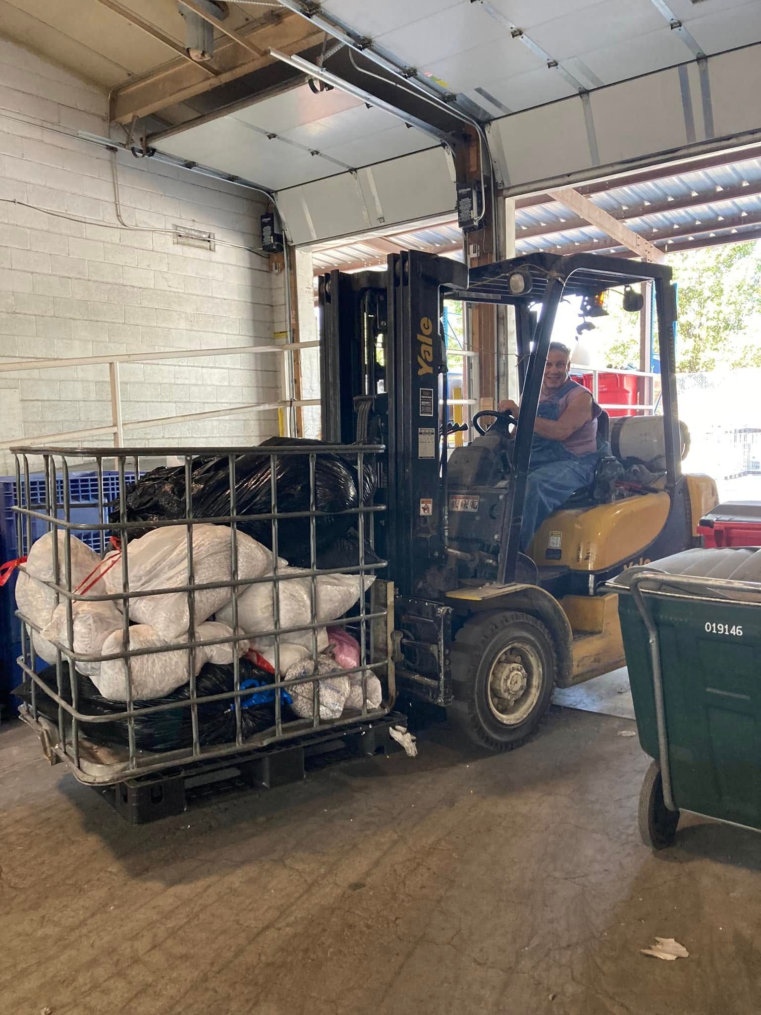 A man is driving a forklift in a garage.