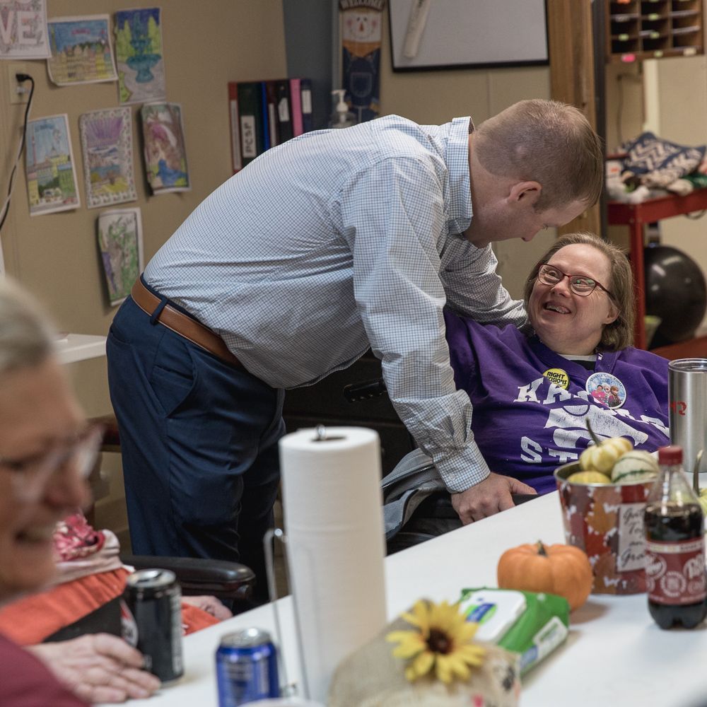 A man is talking to a woman who is sitting at a table