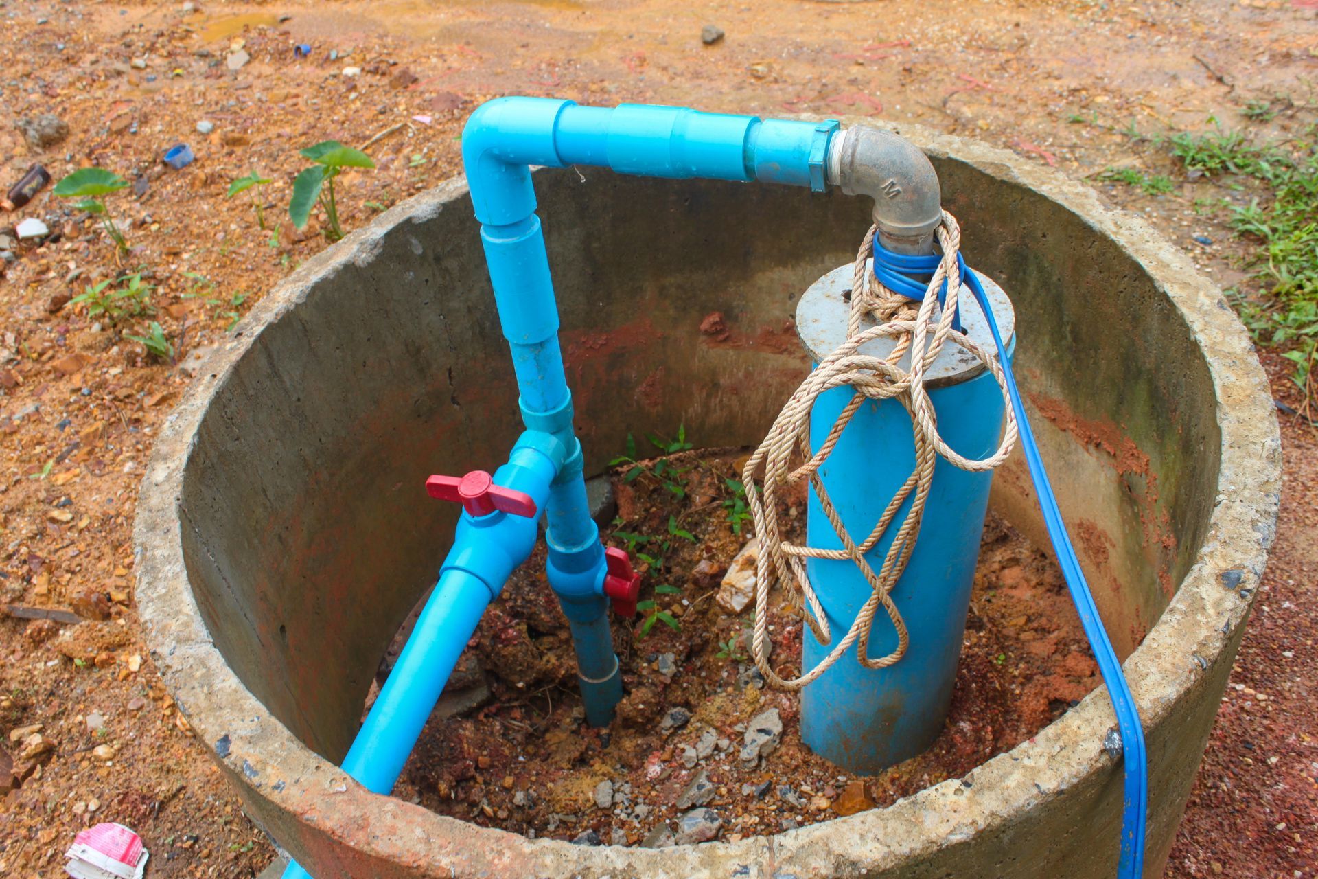 A blue pipe is connected to a concrete ring.