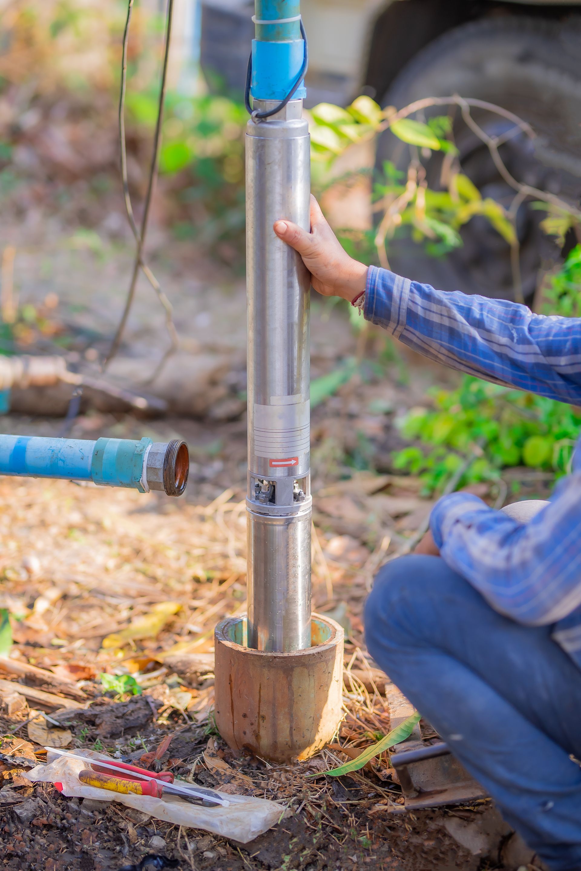 A man is installing a water pump in the ground.