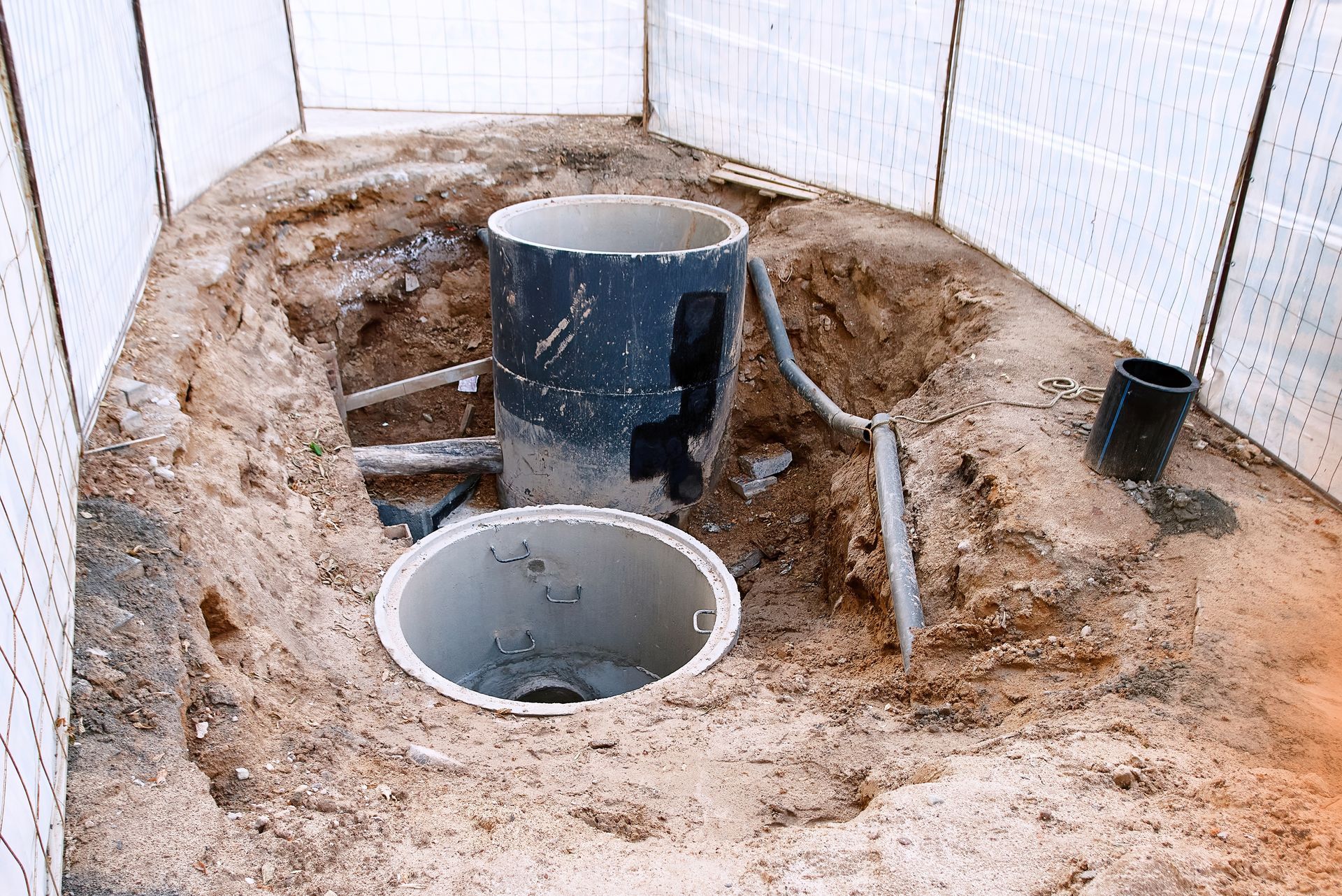 Two concrete rings are sitting on top of a pile of dirt.