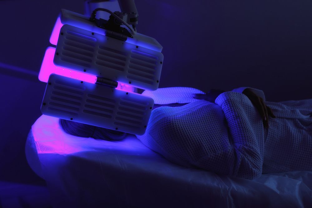 A Woman is Getting a Purple Light Treatment on Her Face — Coastal Skin & Laser in Maroochydore, QLD