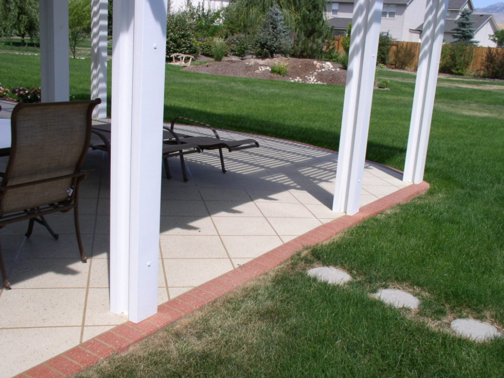 Patio with white columns, brick border, and lawn. Dining set visible.