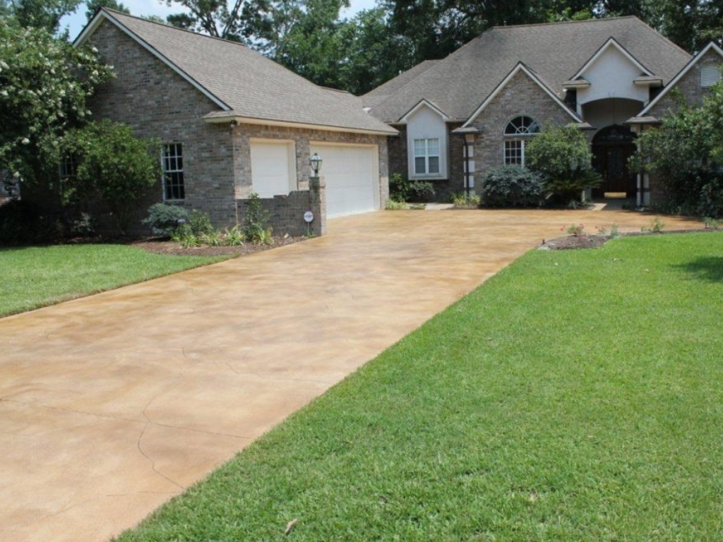 A house with a stained concrete driveway and green lawn.