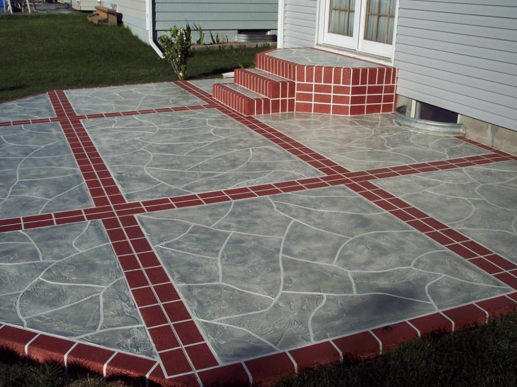 Concrete patio with red brick borders and sections, leading to house steps.