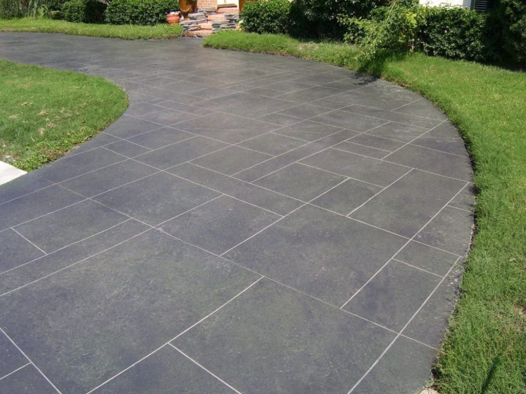 Dark gray tiled driveway curving through green grass.