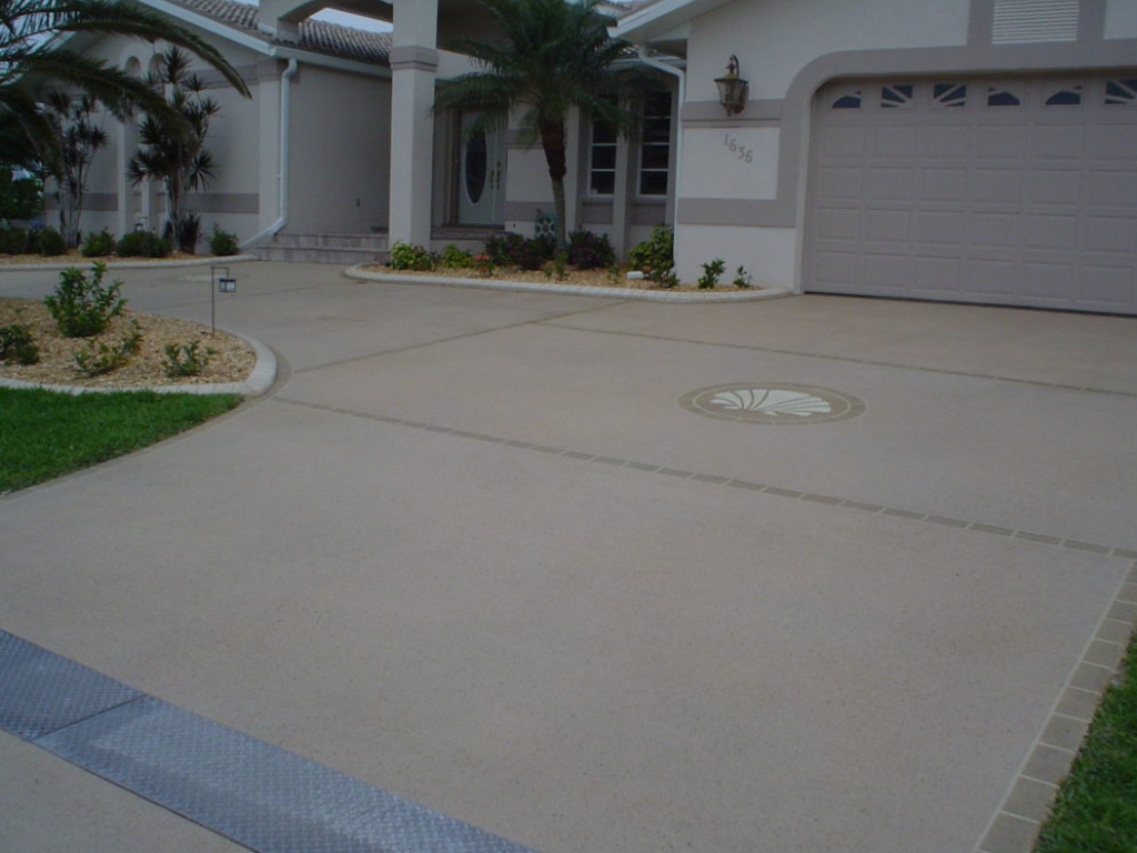 Concrete driveway in front of a house, with a garage and landscaping.