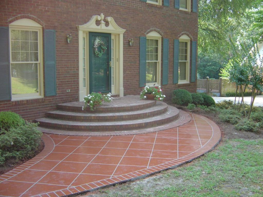Brick home exterior with curved brick pathway and steps leading to a green front door.