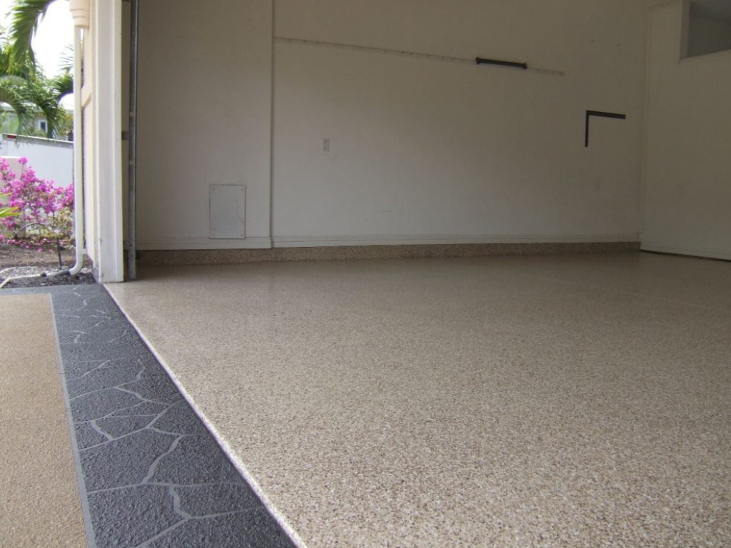 Empty garage with speckled tan floor, open doorway, and a decorative border.