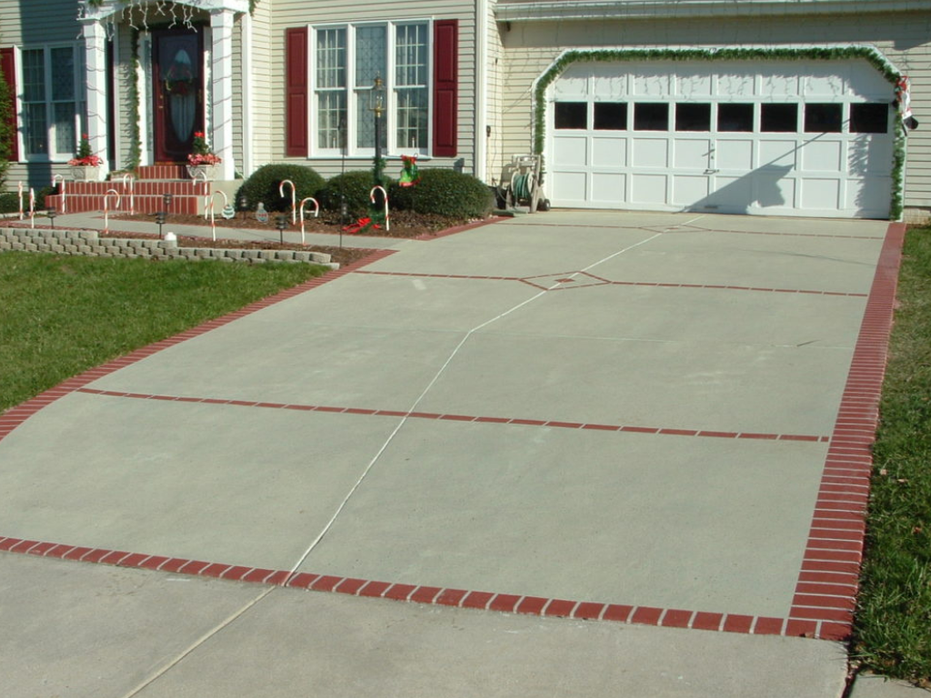 Driveway with red brick border, leading to a house with a white garage door.