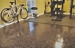 A bike and exercise equipment sit in a room with a shiny, dark floor.