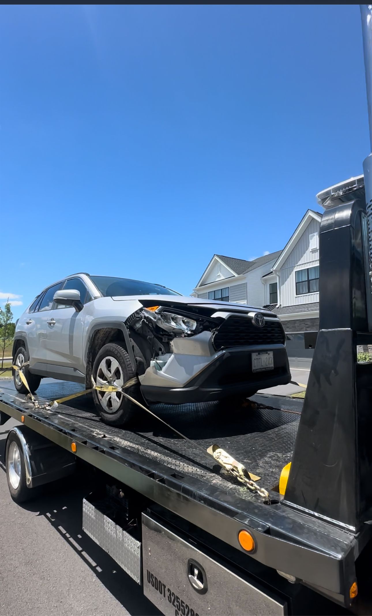 A silver car is sitting on top of a tow truck.