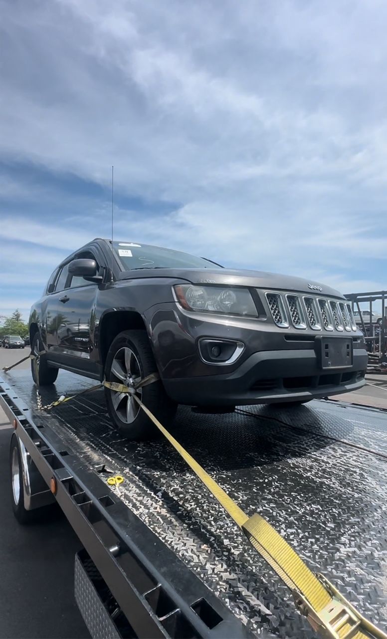 A jeep compass is being towed by a tow truck.