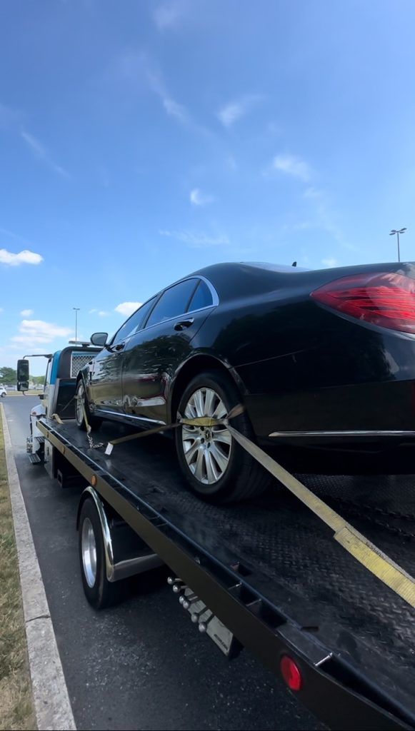 A black car is being towed by a tow truck.
