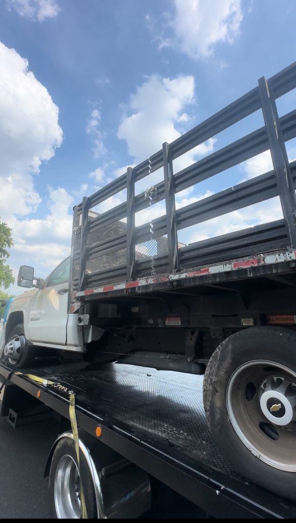 A truck with a fence on the back of it is being towed by a tow truck.