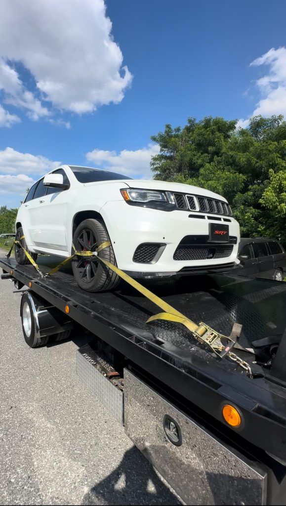 A white jeep grand cherokee is being towed by a tow truck.