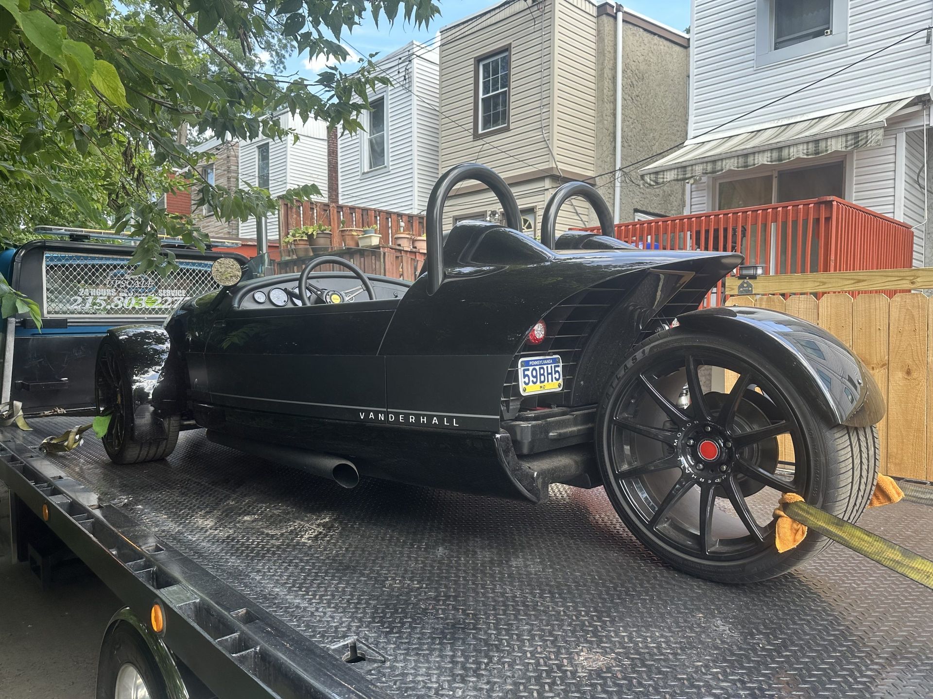 A black three wheeled vehicle is sitting on top of a tow truck.