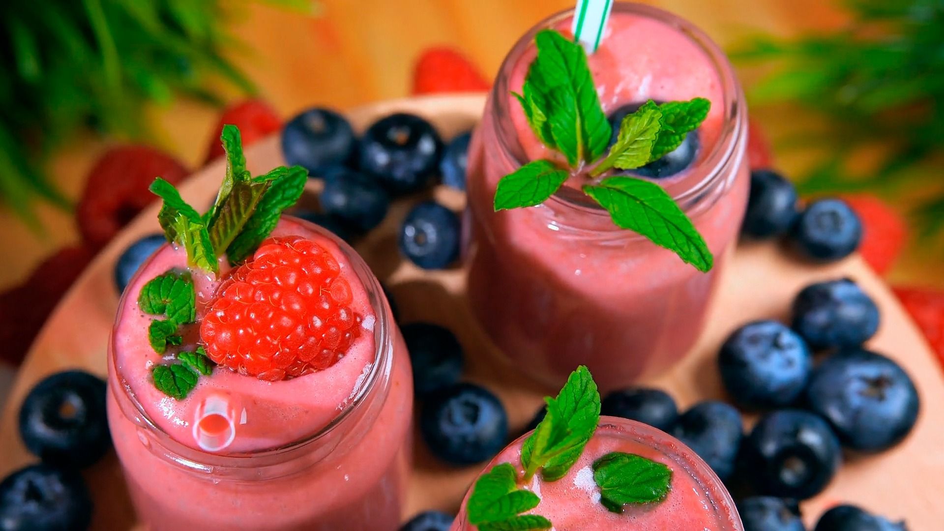 Three smoothies with strawberries and blueberries on a plate