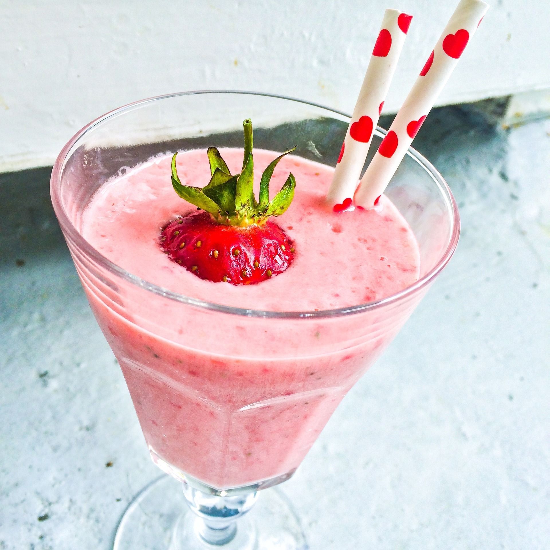 A strawberry fruit is on top of a strawberry smoothie