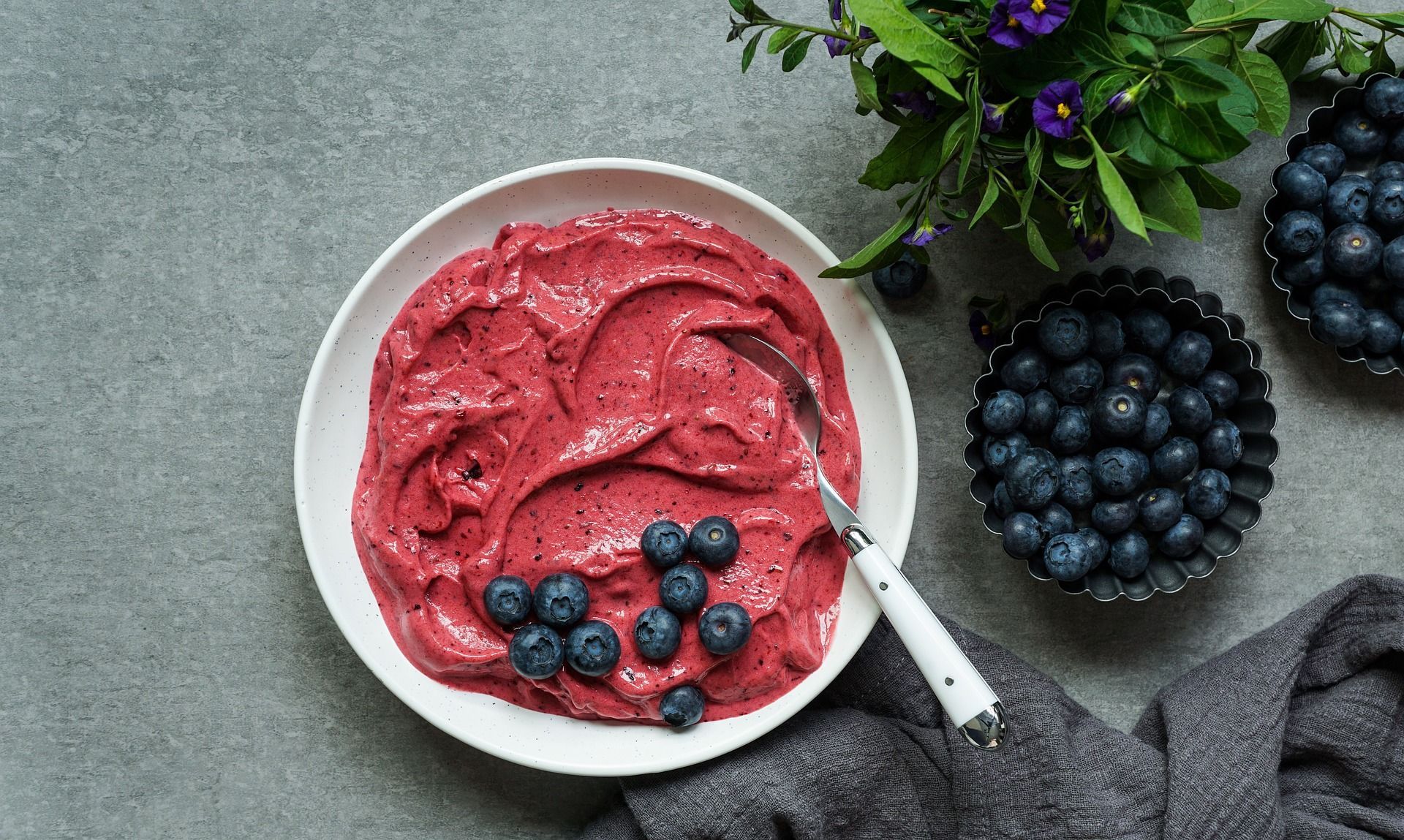 A bowl of smoothie with blueberries and a spoon in it