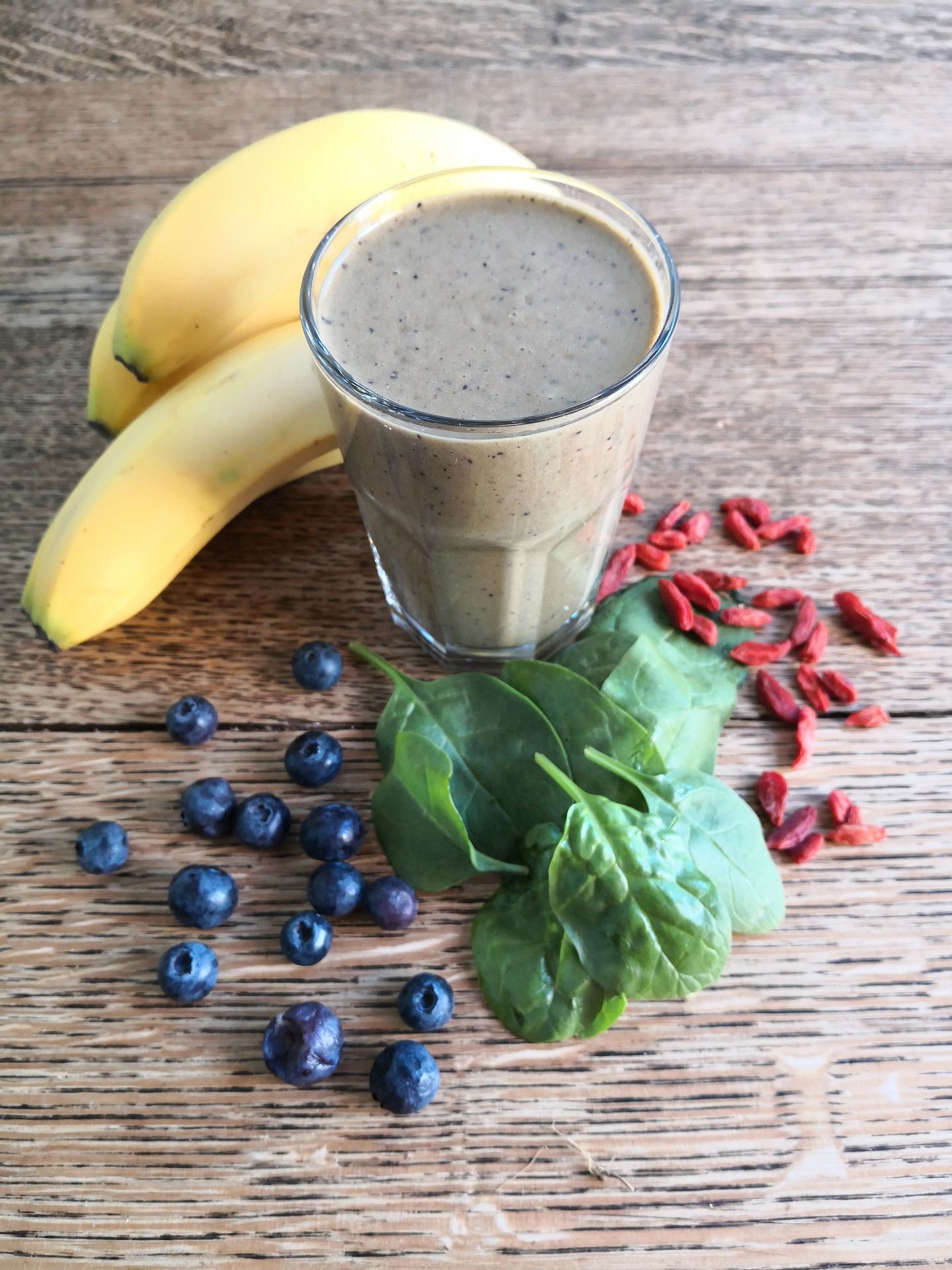 A smoothie with bananas , blueberries , spinach and goji berries on a wooden table