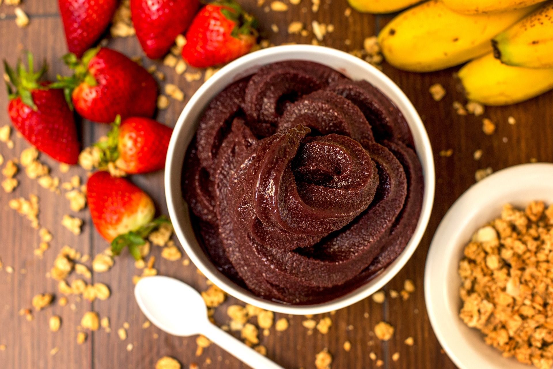 A bowl of açai with strawberries and bananas on a wooden table