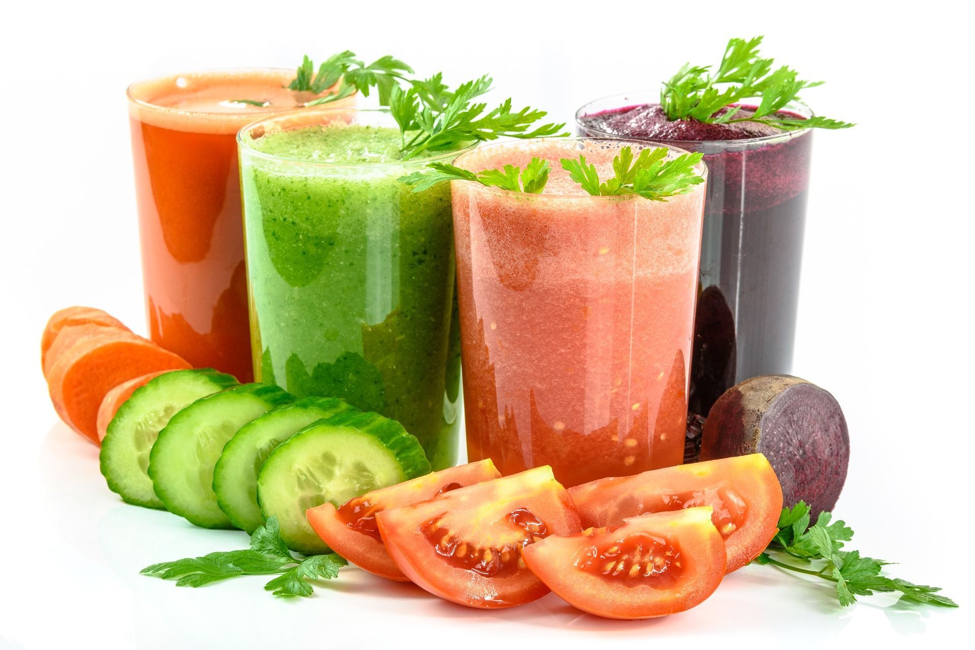 Three smoothies with vegetables in them on a white background