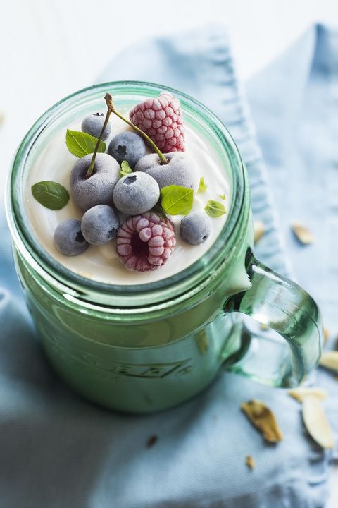 A green mason jar filled with yogurt and berries