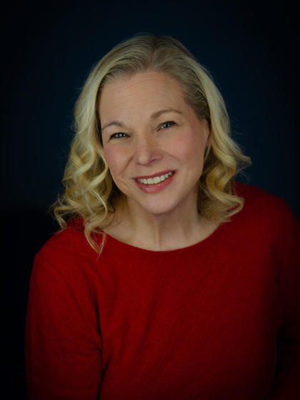 A woman with blonde hair and a black shirt is smiling for the camera.