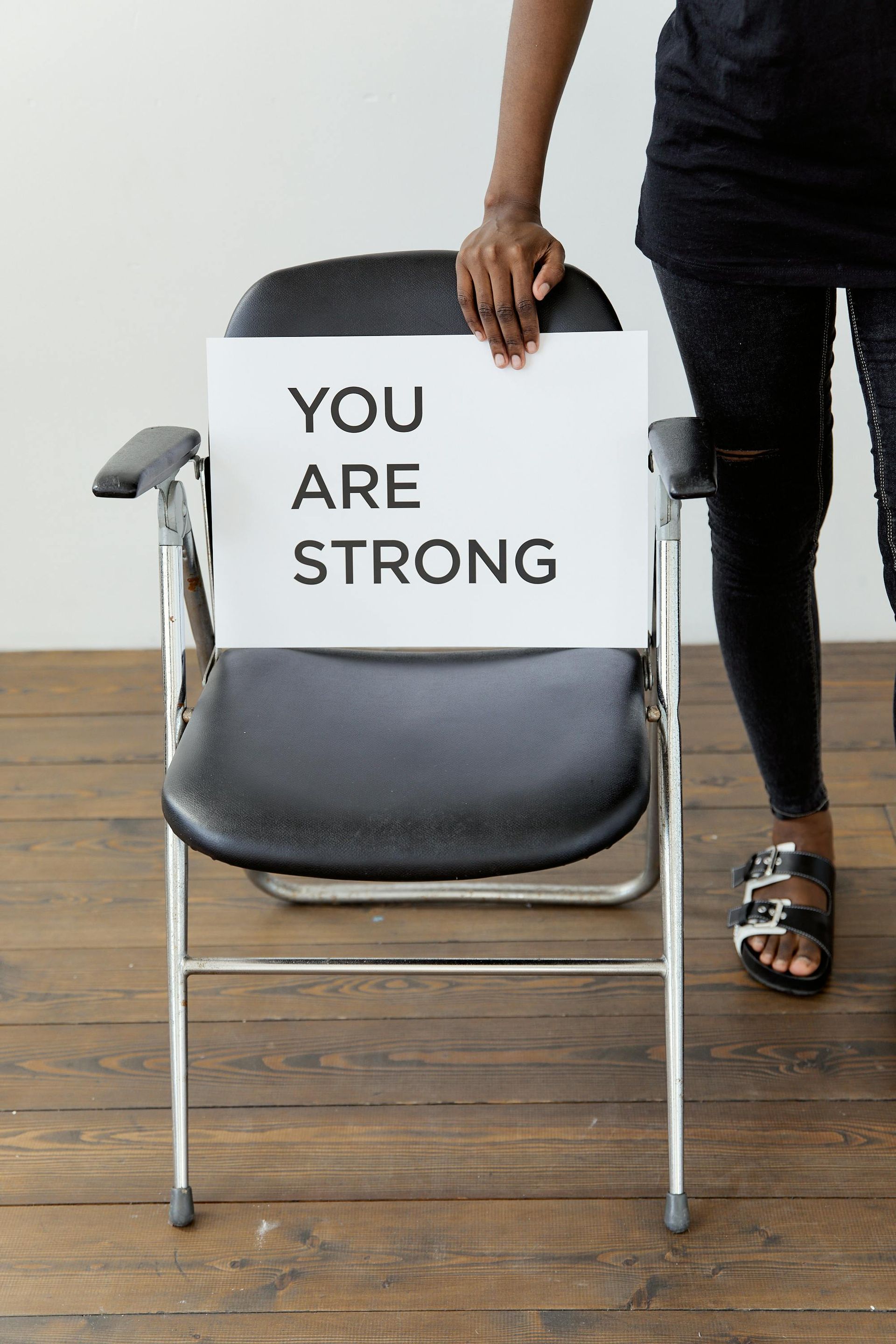 A person holds a sign on a chair that reads 