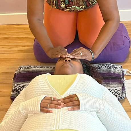 Woman receiving energy healing treatment; laying down with hands on forehead.