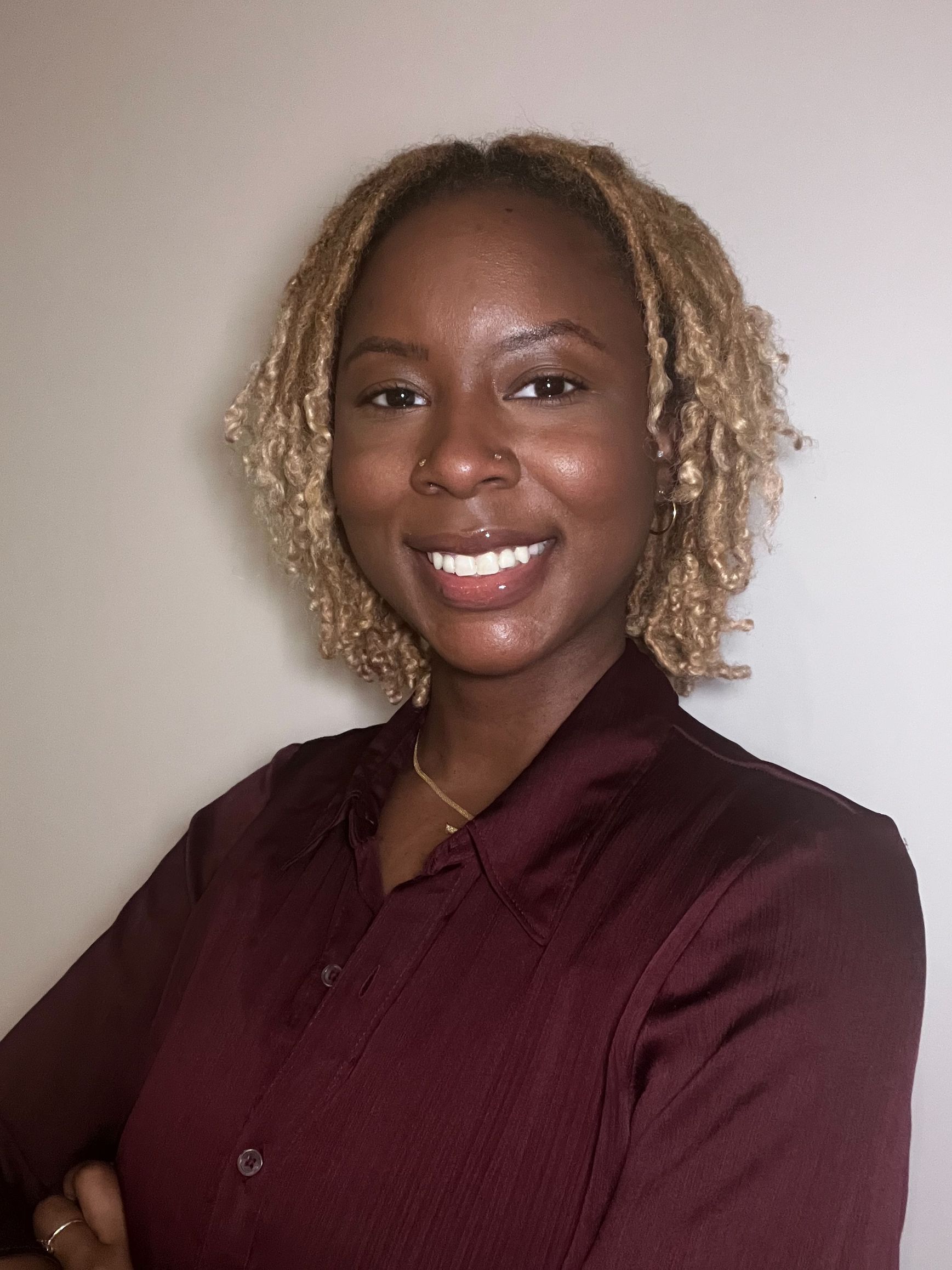 A woman wearing a white shirt and graduation cap is smiling for the camera.