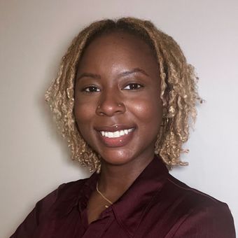 A woman wearing a pink sweater and hoop earrings is smiling for the camera.
