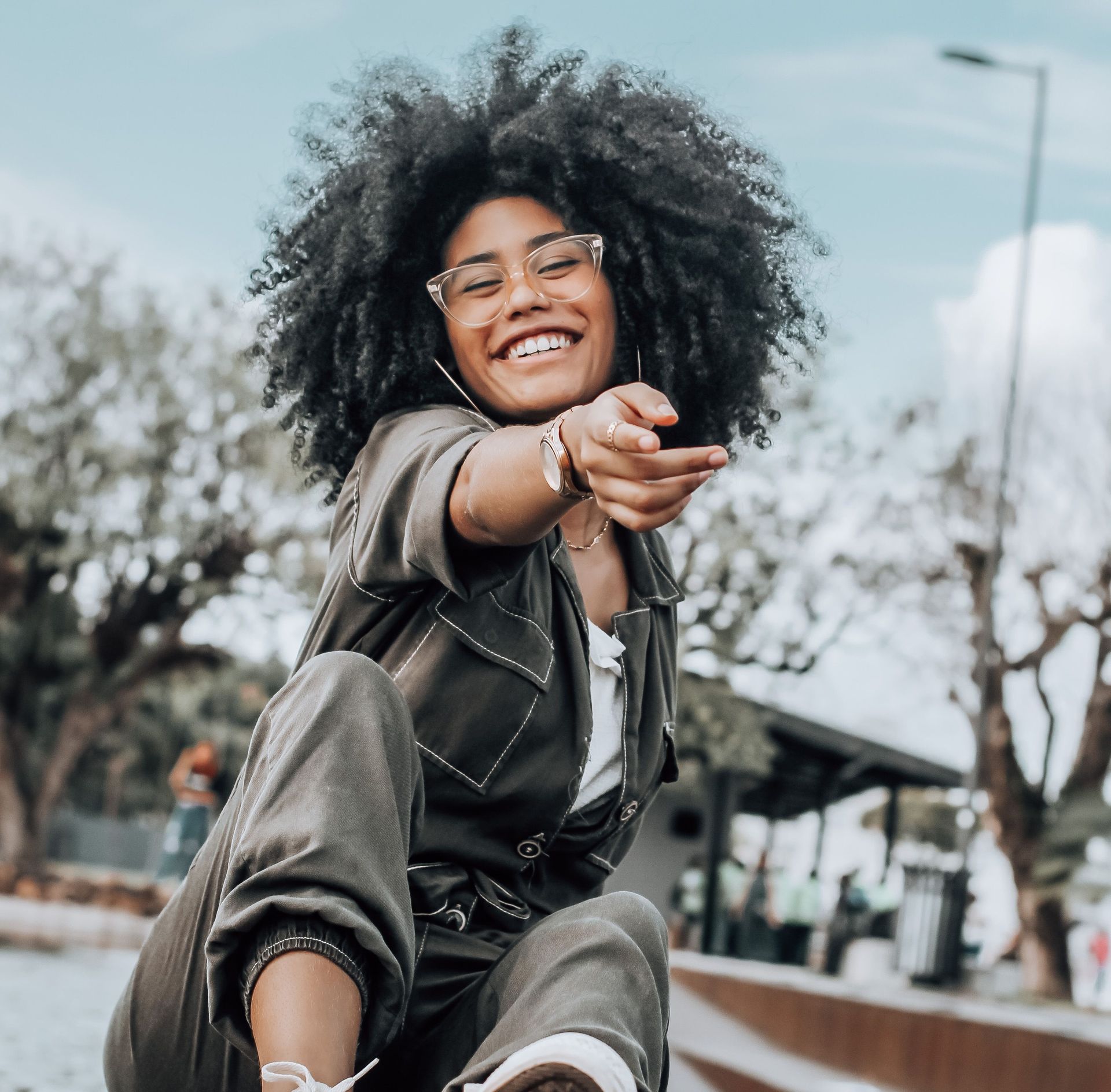 A black woman with glasses smiles for the camera