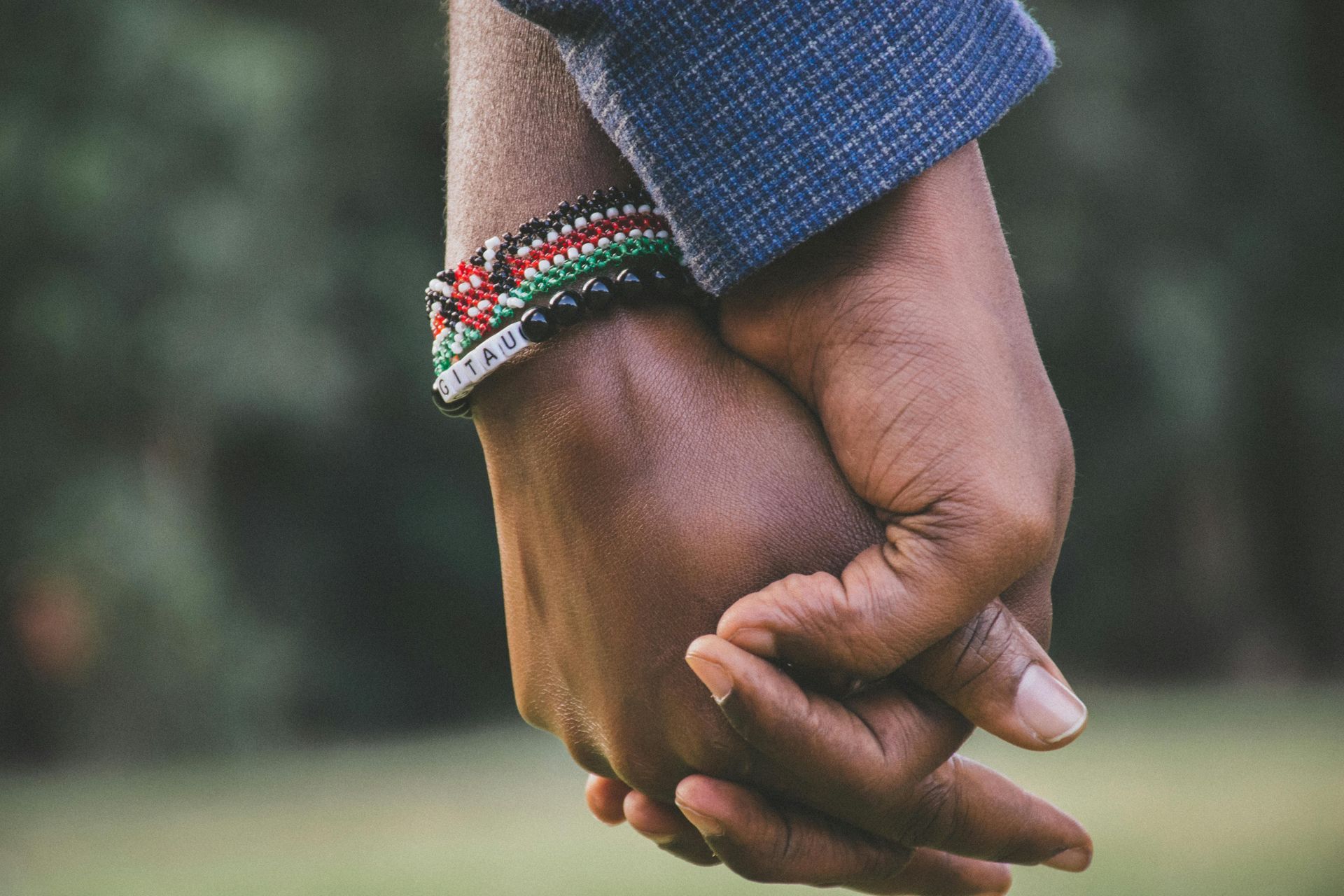 A man and a woman are holding hands with bracelets on their wrists.