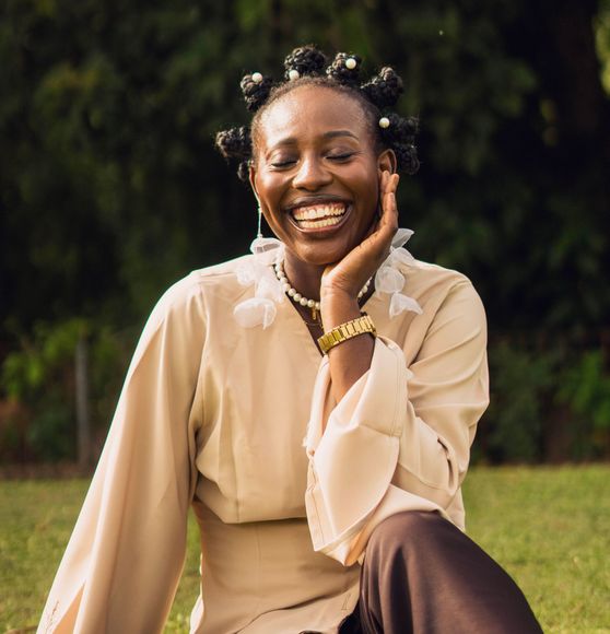 A black woman with bantu knots smiles for the camera