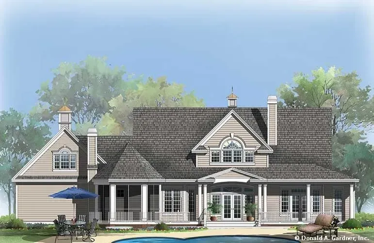 Beige house with porch, pool, and outdoor furniture. Cloudy sky and trees in the background.