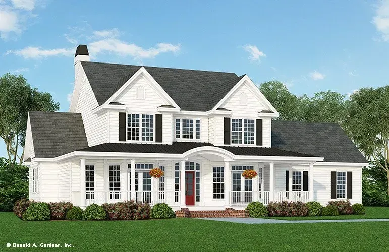 White farmhouse with black shutters, porch, and red door, set on a green lawn.