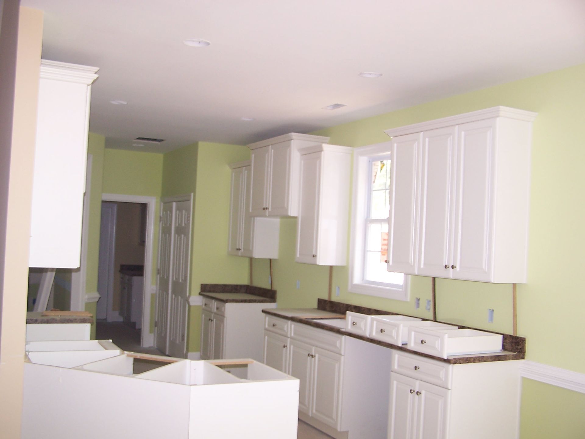 White kitchen cabinets against light green walls during renovation.