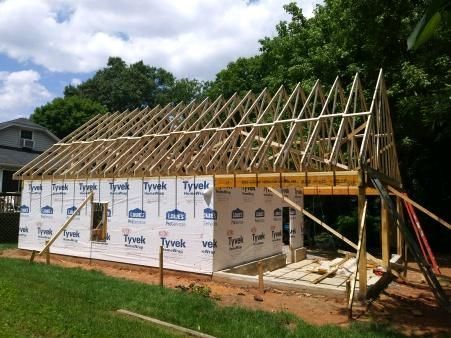 Construction site with wooden roof trusses on a framed structure wrapped in Tyvek.