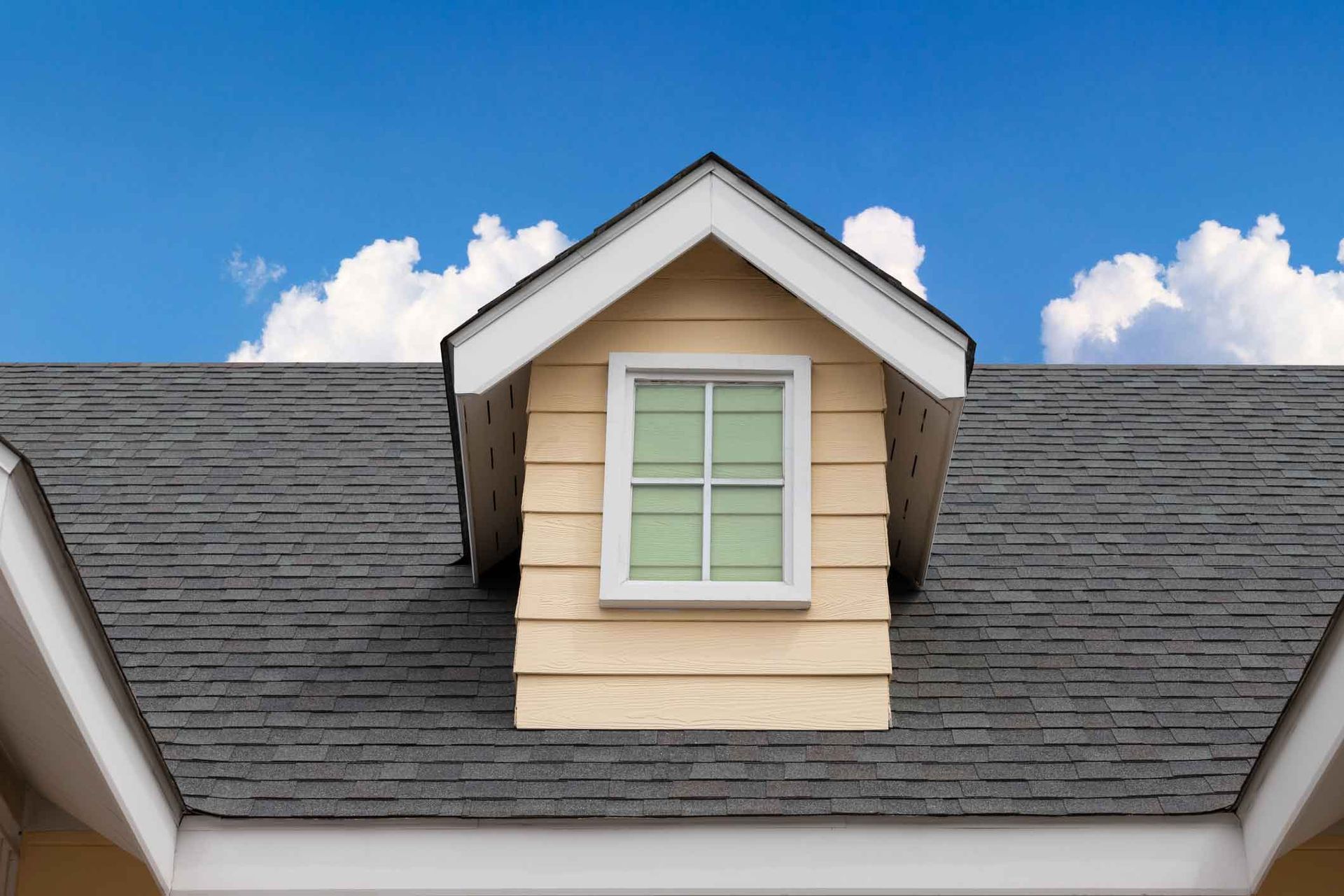 A house with a window on the roof and a blue sky in the background