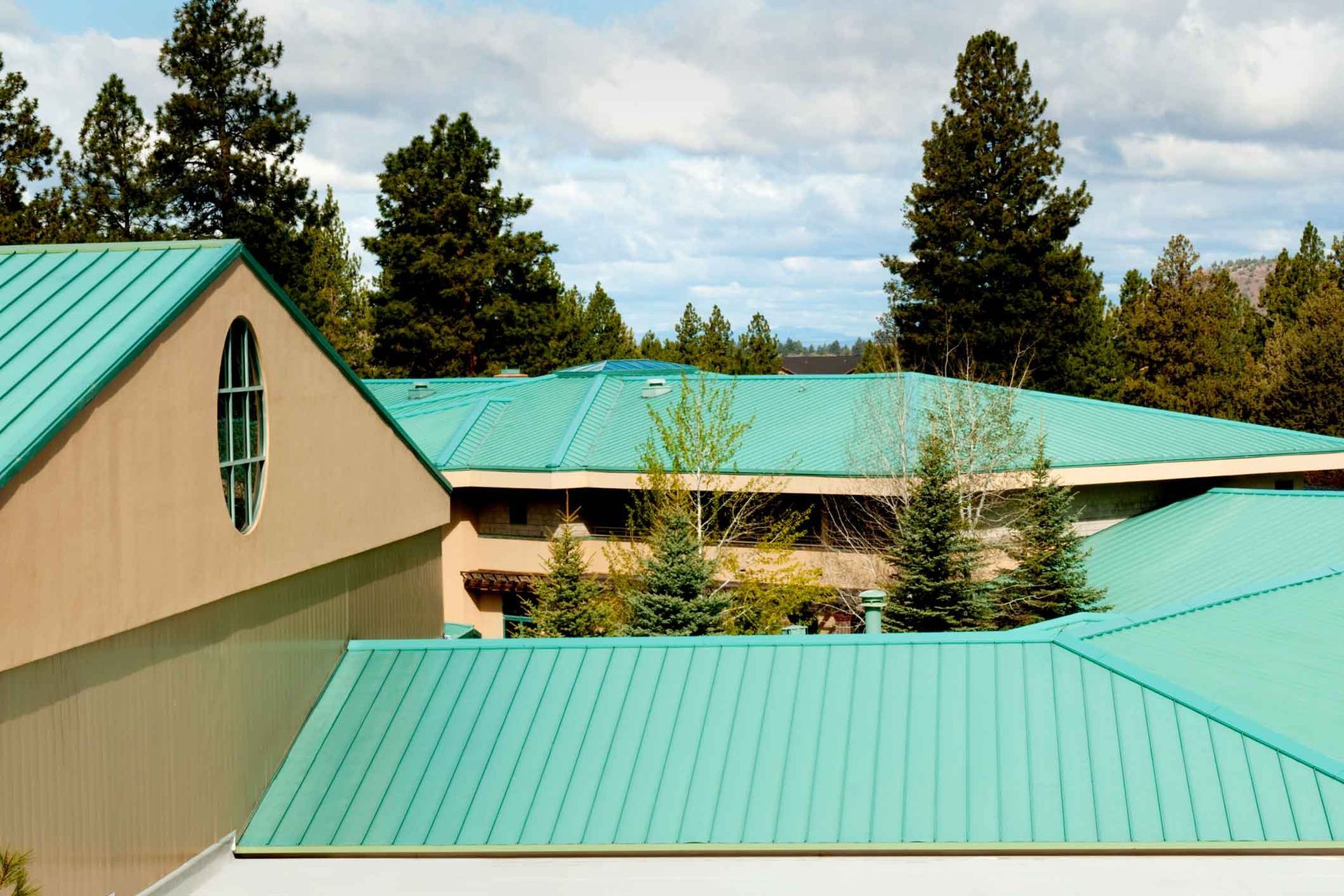 A building with a green roof and trees in the background