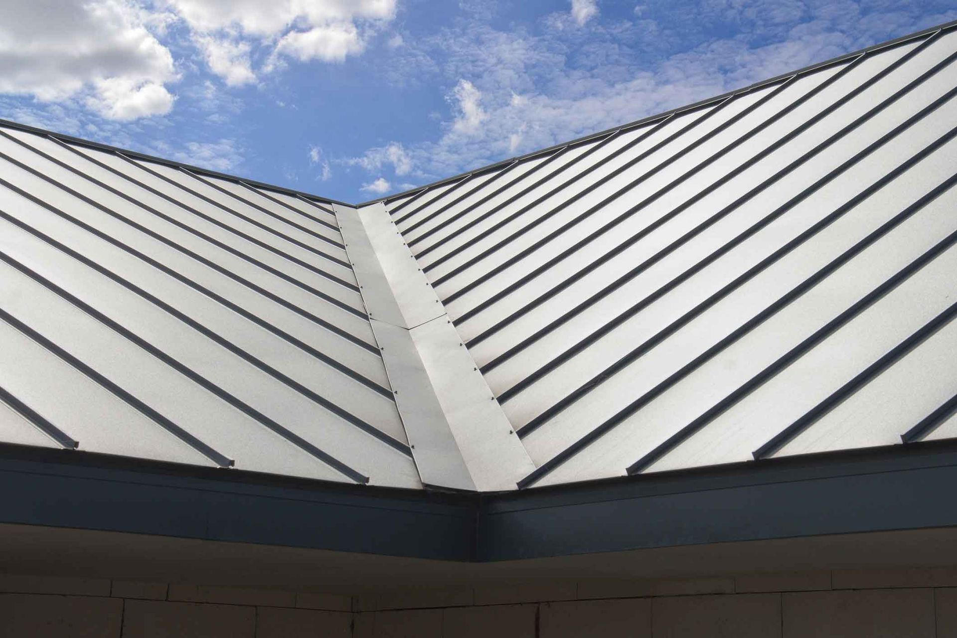 A close up of a metal roof with a blue sky in the background.