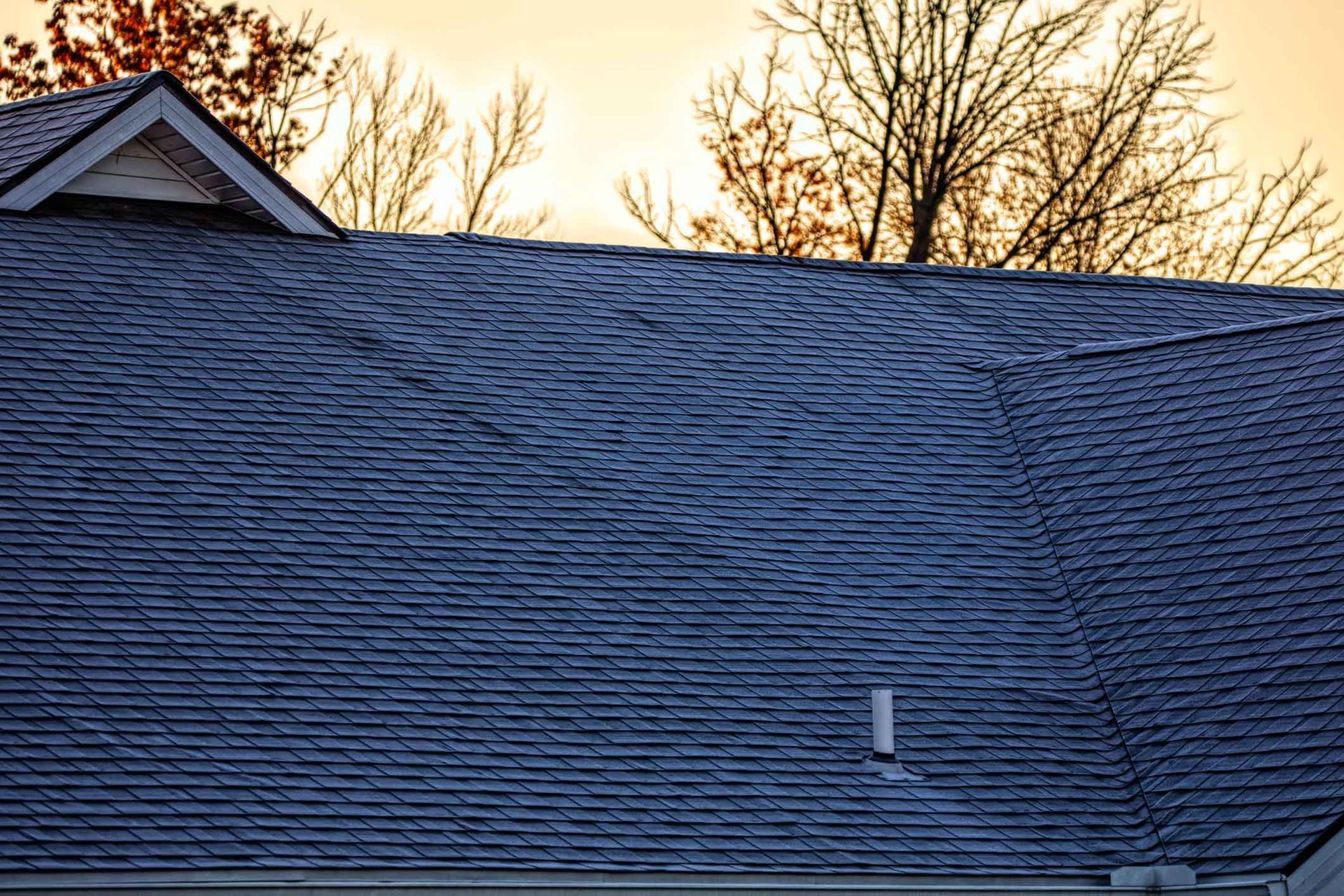 The roof of a house with a sunset in the background.