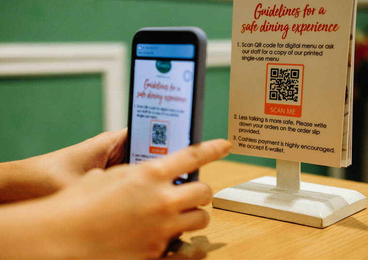 A person is using a cell phone next to a sign that says guidelines for a safe dining experience