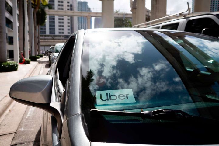 A silver uber car is parked on the side of the road.