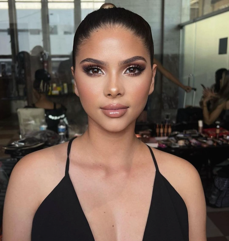 A woman in a black dress is looking at the camera